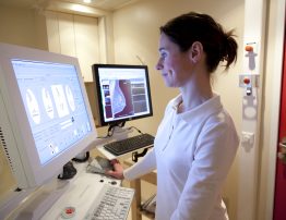 Female radiology technician performs mammography test on computer