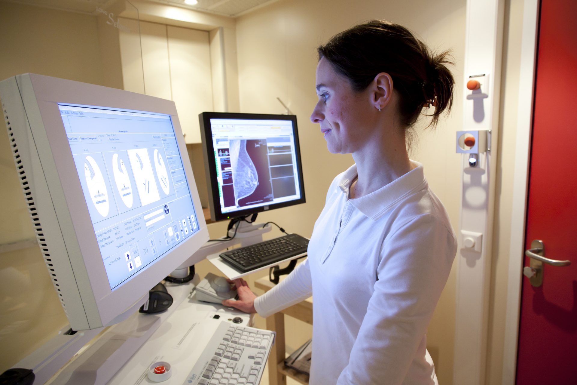 Female radiology technician performs mammography test on computer