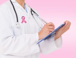 Doctor writing on clipboard against pink