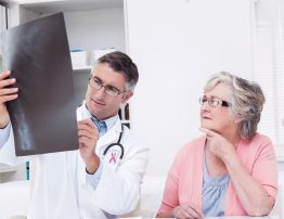 Pink awareness ribbon against doctor explaining x-ray to female patient