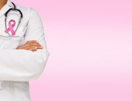 Mid section of a female doctor with skeleton model against pink